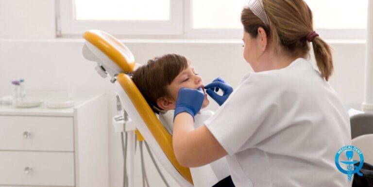 Obraz przedstawia dentyste leczącą ząb mleczny małemu dziecku. Dziecko leży na fotelu dentystycznym, a lekarz, ubrana na biało, wykonuje zabieg w wyposażonym gabinecie stomatologicznym.