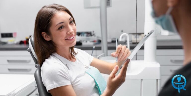 Obraz przedstawia młodą uśmiechniętą kobietę siedzącą na krześle dentystycznym podczas wizyty u stomatologa. Trzyma tablet, na którym prawdopodobnie omawia z lekarzem plan leczenia lub procedury implantologiczne. Sceneria wskazuje na gabinet stomatologiczny wyposażony w typowe dla tej dziedziny medycznej sprzęty i narzędzia.