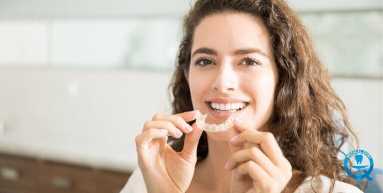 Kobieta trzymająca przezroczysty aparat retencyjny przy ustach, ilustrujący temat retencji po leczeniu ortodontycznym.