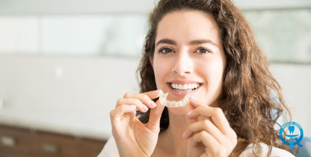 Kobieta trzymająca przezroczysty aparat retencyjny przy ustach, ilustrujący temat retencji po leczeniu ortodontycznym.