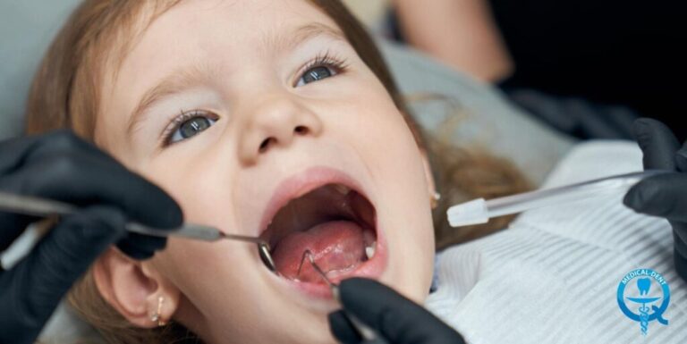 Dziecko leżące na fotelu dentystycznym z otwartą buzią, podczas gdy dentysta trzyma narzędzia przy zębach.