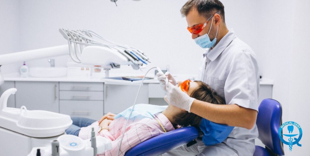 Dentysta w gabinecie stomatologicznym przeprowadza zabieg przygotowawczy do wybielania zębów u pacjentki w fotelu dentystycznym.